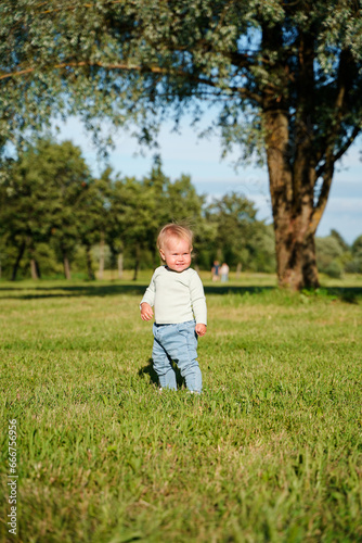 Happy little child baby 1 year in the park in summer, outdoor walking