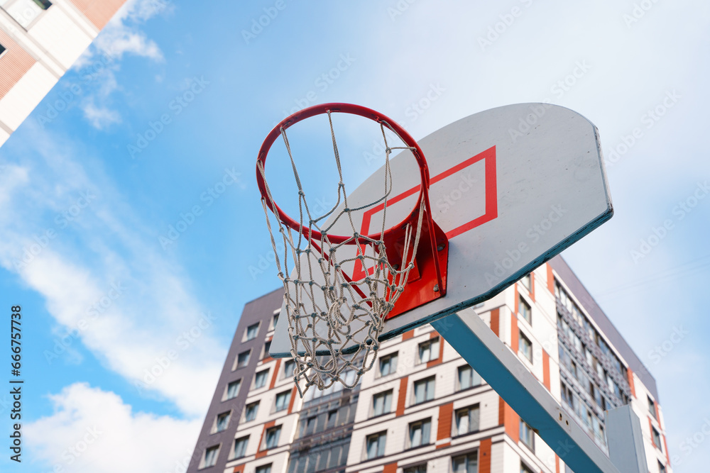 Basketball hoop on the background of the sky and residential multi-storey buildings