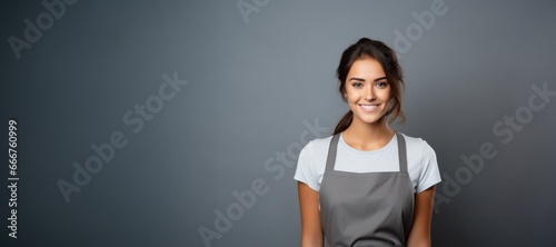 Smiling attractive young female restaurant worker looking at the camera on gray background photo