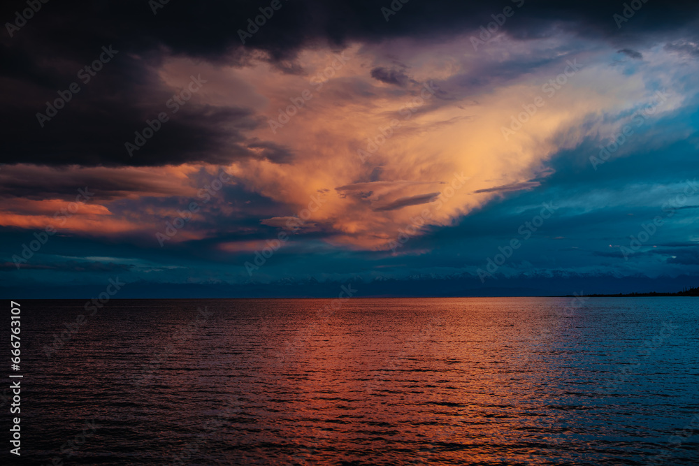 Dramatic landscape of Issyk-Kul lake with mountains and clouds at sunset, Kyrgyzstan