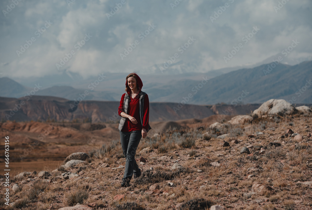Young smiling woman tourist walks in the mountains
