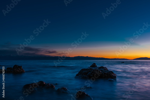 Lake landscape with big stones at dark sunset, long exposure blurred motion