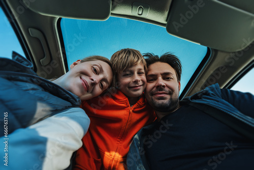 Happy parents with their son posing in car interior