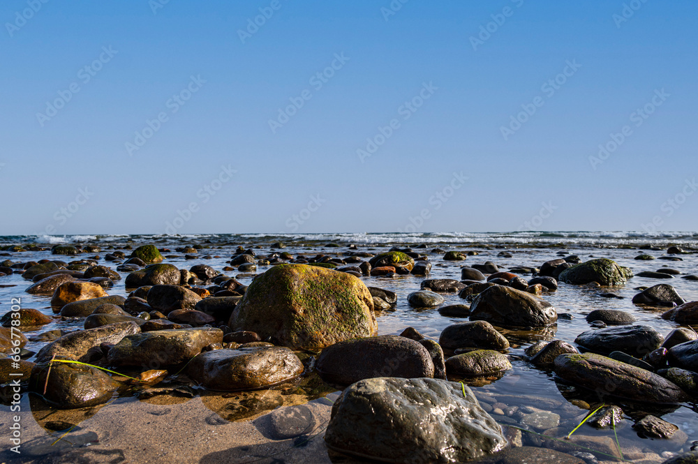 Sea water laps the rocks on the stone beach. Sea water laps the rocks on the stone beach.