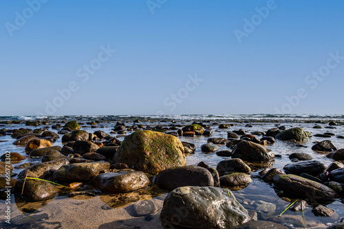 Sea water laps the rocks on the stone beach. © Bernhard