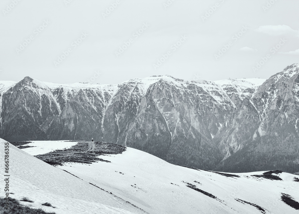 Obraz premium Scenic view from Baiului Mountains with the snowy peaks of Bucegi Mountains. Carpathians in Romania. Black and white photography.