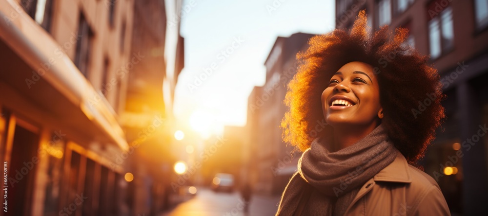 Beautiful charming young black woman posing at a city streets sunset looking up very happy with hope and peaceful mind