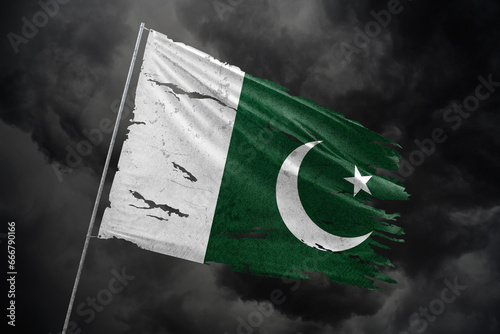 Pakistan torn flag on dark sky background.