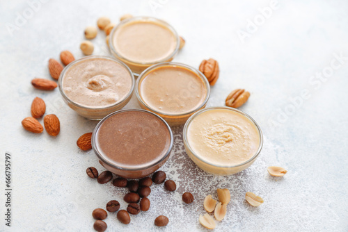 Homemade nuts butter in a glass jars with various nuts.