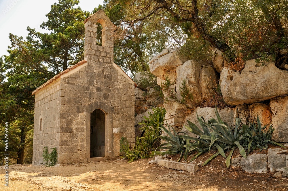 a stone building next to a tree and rocks with plants: Mljet, Croatia
