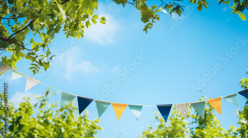 string of colorful pennant against blue sky in the garden as a summer party decoration photo