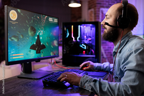 Gamer playing classic arcade action space videogame, shooting meteorites using lazer beams. Man enjoying leisure time at home using high tech gaming PC to solve missions in singleplayer game
