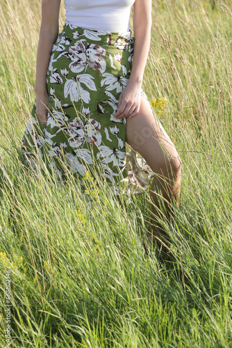 Candid outdoor portrait on the meadow of young woman linen skirt and white top. Casual summer fashion. 
