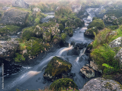 Irish nature scene with small creek in green fields with rocks and fog in the background. Connemara  Ireland. Hard weather conditions. Nature  travel and sightseeing.