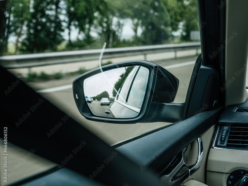 Driver's perspective on the rearview mirror, emphasizing the importance of safety and awareness while commuting on a highway or navigating city streets Driver's perspective on the rearview mirror, emphasizing the importance of safety and awareness while commuting on a highway or navigating city streets