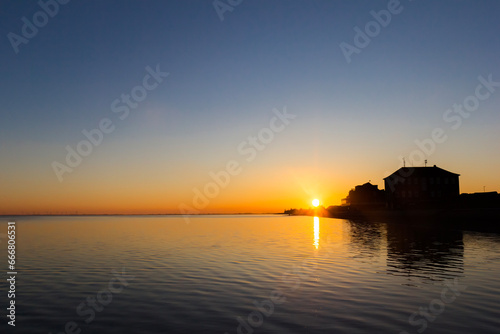 Sun going down behind the dike in Wilhelmshaven, Germany photo