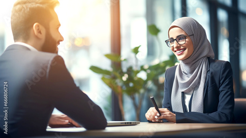 smiling middle eastern business woman with hijab talking with client