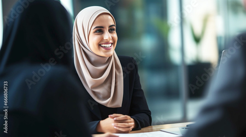 smiling middle eastern business woman with hijab talking with client photo