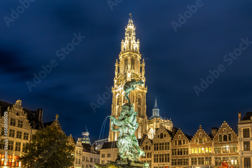 Brabo-Brunnen auf dem Grote Markt in Antwerpen, umgeben von Gilde- und Zunfthäusern und im Hintergrund die Liebfrauenkathedrale – Nachtaufnahem photo