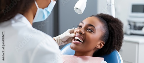 A young African American dentist examining a female patient s teeth during a dental appointment at a clinic