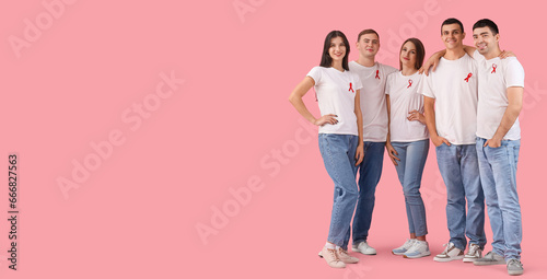 Young people with red ribbons on pink background with space for text. World AIDS Day photo