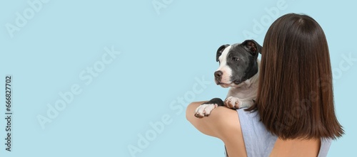 Young girl holding cute puppy on light blue background with space for text