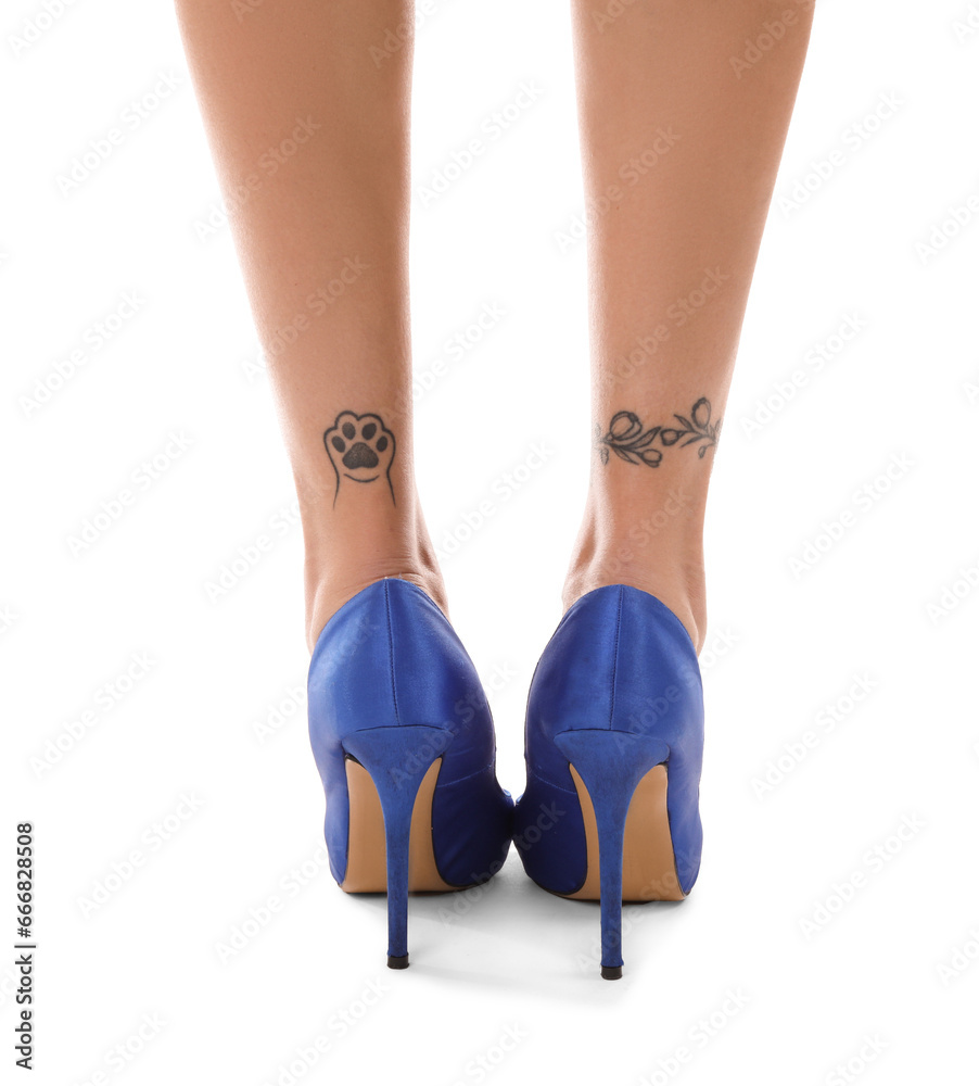 Tattooed female legs in heels on white background, back view Tattooed female legs in heels on white background, back view