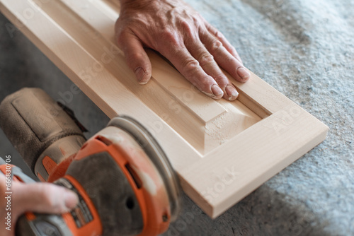 Carpenter's hands using power sander on woodwork