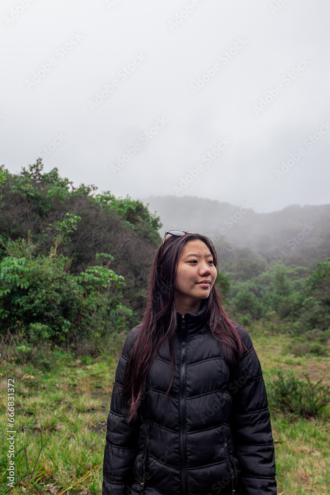 
beautiful Asian girl with red hair enjoying nature and the cold at the Poas Volcano in Costa Rica, with a calm atmosphere