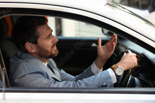 Stuck in traffic jam. Stressed driver in his car, view from outside