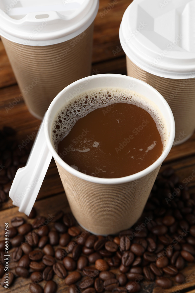 Coffee to go. Paper cups with tasty drink and beans on wooden table, closeup Coffee to go. Paper cups with tasty drink and beans on wooden table, closeup