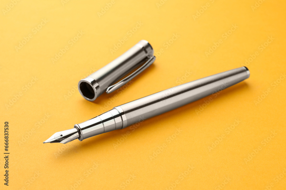 Stylish silver fountain pen with cap on yellow background Stylish silver fountain pen with cap on yellow background