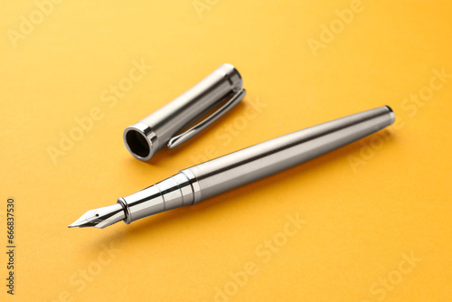 Stylish silver fountain pen with cap on yellow background