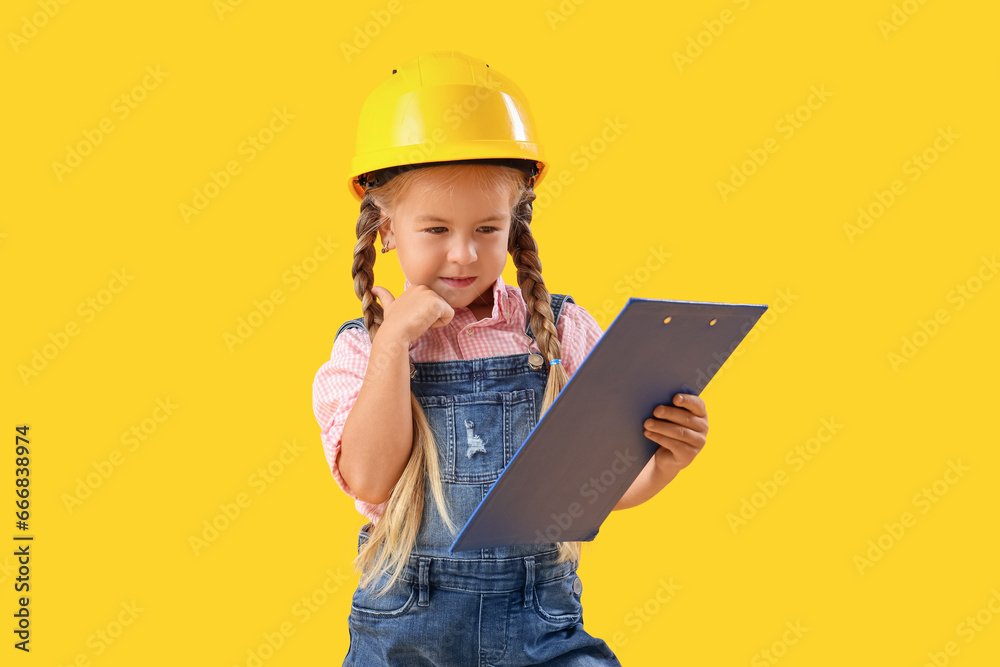 Cute little builder girl with clipboard on yellow background Cute little builder girl with clipboard on yellow background