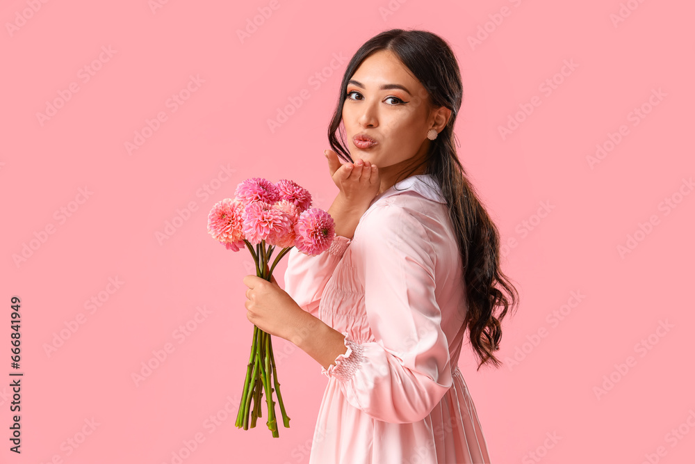 Beautiful young Asian woman with bouquet of dahlias blowing kiss on pink background Beautiful young Asian woman with bouquet of dahlias blowing kiss on pink background