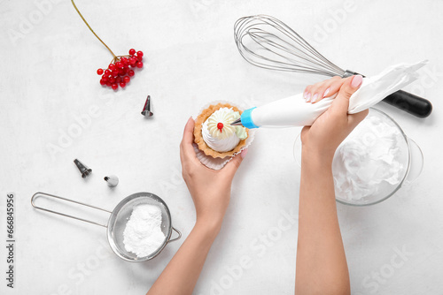 Female confectioner decorating tasty cake on white background photo