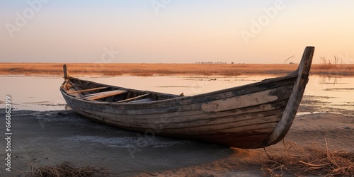 A traditional Marsh Arab canoe known as a Mashoof abandoned on the dry earth of the southern marshes of Iraq during a harsh summer drought caused by climate change and political instab   Generative AI
