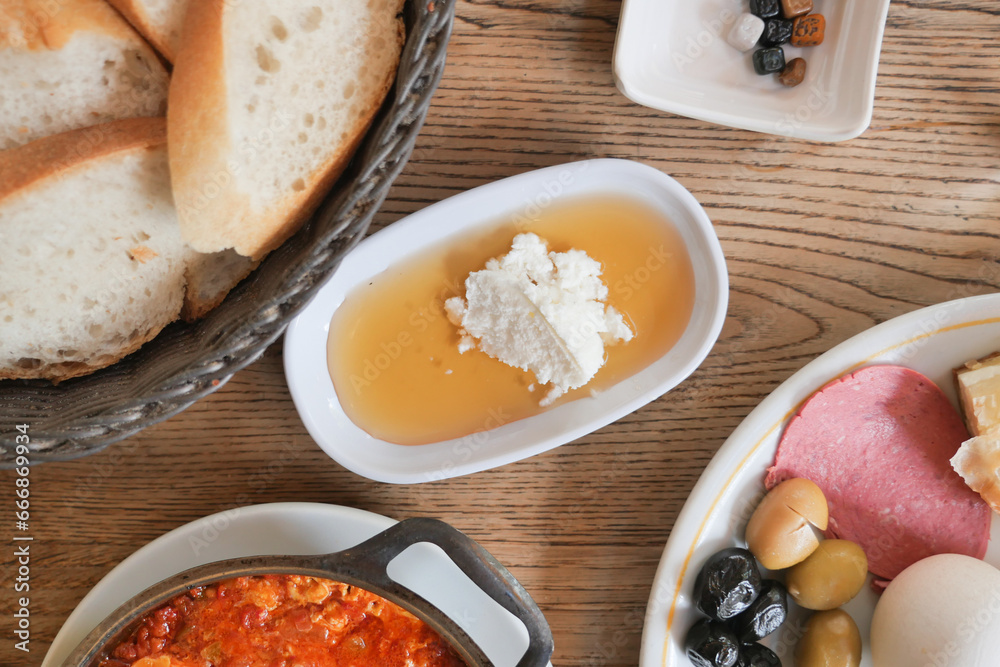 butter cream and honey in a bowl with olive, salami and bread on table butter cream and honey in a bowl with olive, salami and bread on table
