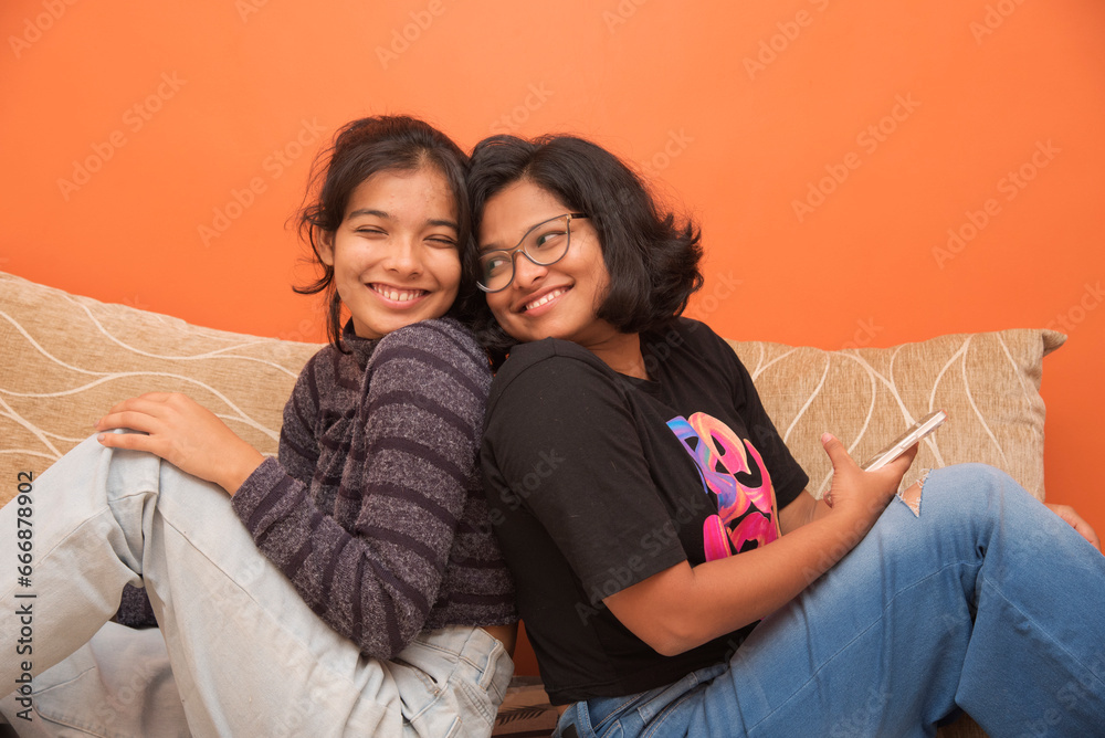 Beautiful dark-skinned young girls with cute smiles are having fun on bed at home