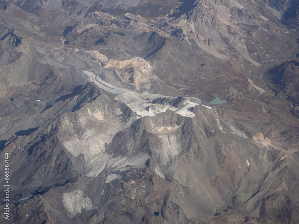 Flying over the European Alps during fall season. Landscape at the glaciers. Melting of glaciers due to global warming. Aerial view from the airplane window Flying over the European Alps during fall season. Landscape at the glaciers. Melting of glaciers due to global warming. Aerial view from the airplane window