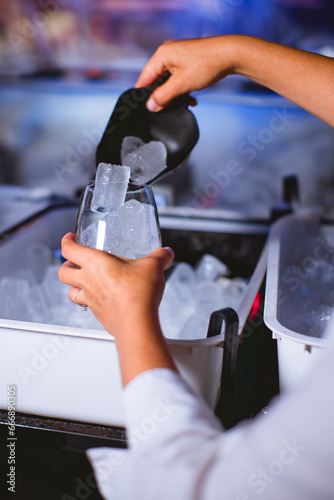 Female Bartender Pouring Ice for Cocktail at Party photo