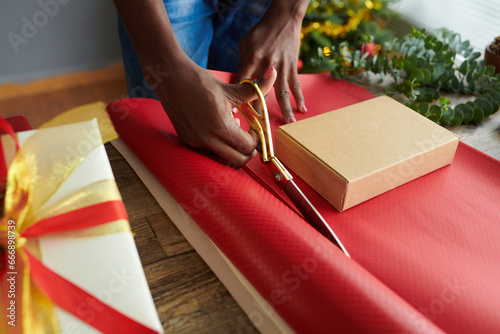 Hands of woman cutting paper and wrapping presents for Christmas