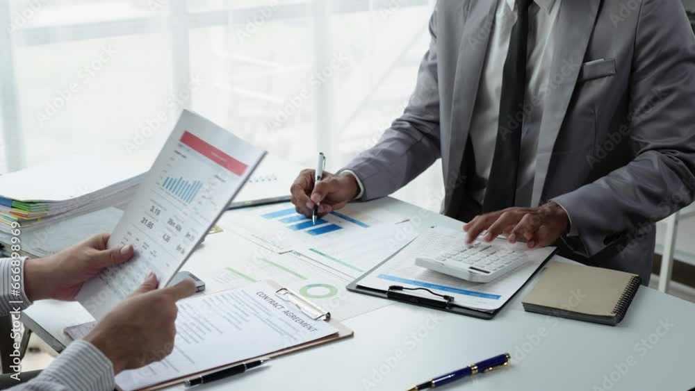 Finance business people or accountants point to the graph and use a calculator to calculate company income, expenses, taxes, and employee bonuses for Next year's improvement plan. Finance business people or accountants point to the graph and use a calculator to calculate company income, expenses, taxes, and employee bonuses for Next year's improvement plan.