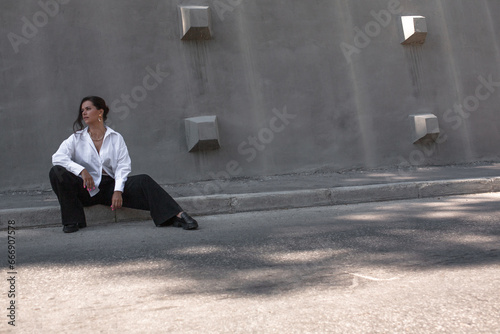 A beautiful woman walking in the street of the city. A business woman looking sidesways. the female wearing the style basic outfit,  black shortsrts and white shirt