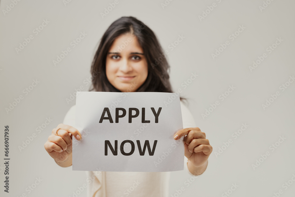 Woman presents 'APPLY NOW' with hopeful eyes Woman presents 'APPLY NOW' with hopeful eyes