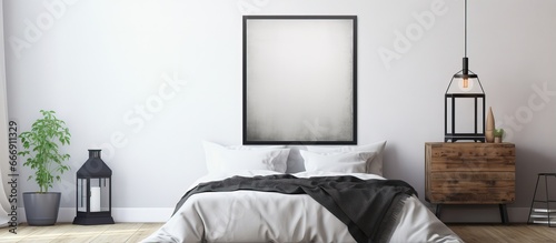 A monochromatic poster on the headboard of a plain bedroom accompanied by a lantern on a bedside table photo