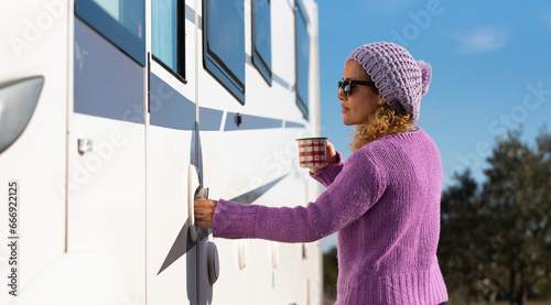 One pretty woman open the door of her camper van ready to leave and start travel adventure alone, Empowerment female people driving rv vehicle. Alone tourist lady with violet pullover enter on camper photo