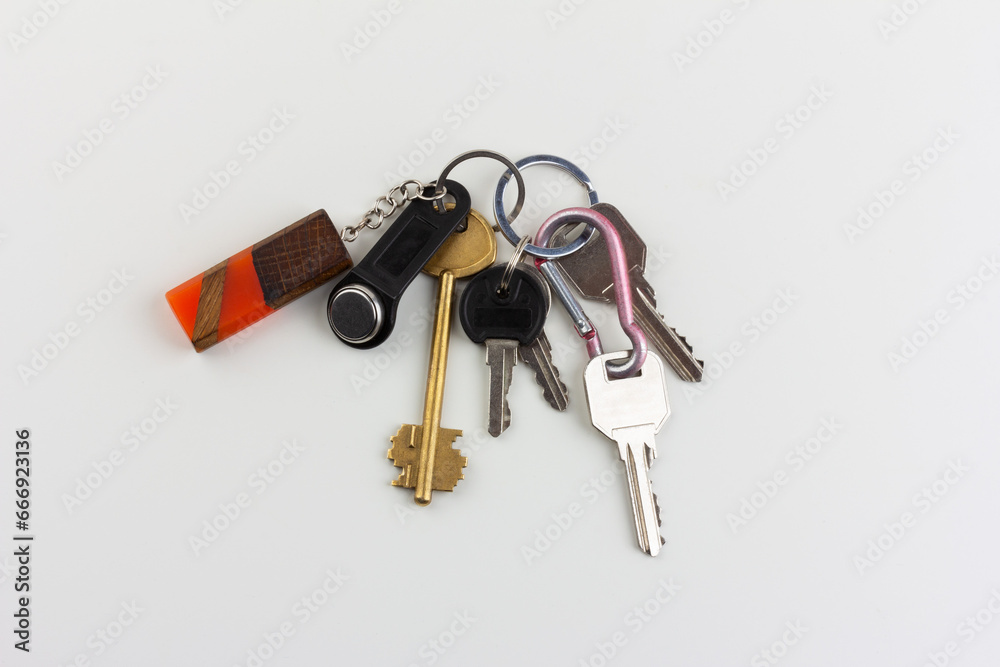 a bunch of door keys with a magnetic security key and an orange epoxy wooden keychain on a white background top view
