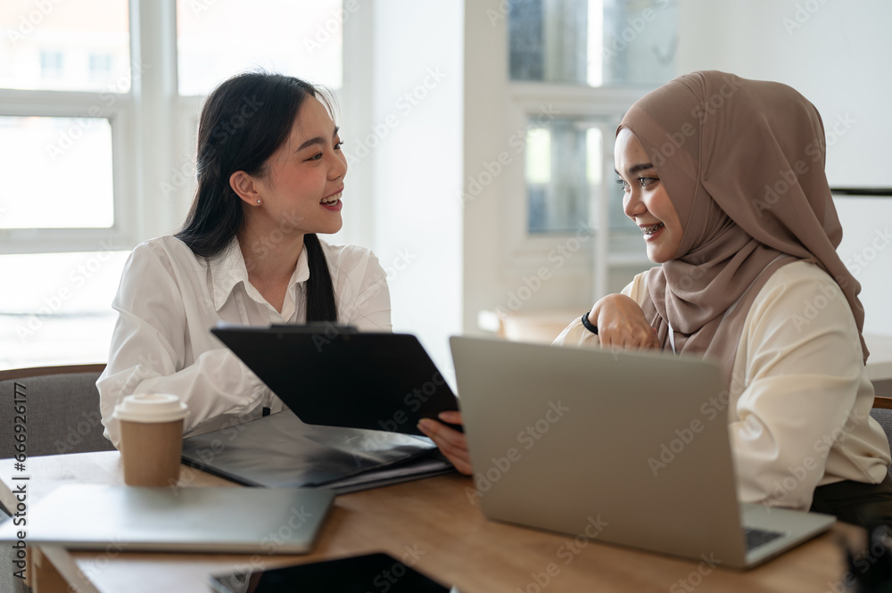 An attractive Asian businesswoman and a beautiful Asian-Muslim businesswoman are working together. An attractive Asian businesswoman and a beautiful Asian-Muslim businesswoman are working together.