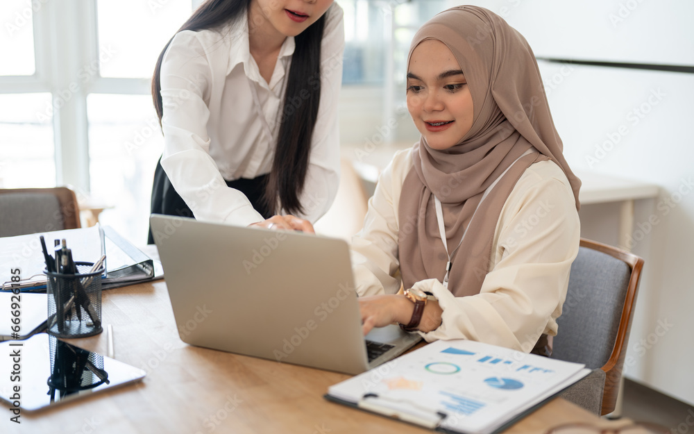 An attractive Asian businesswoman and a beautiful Asian-Muslim businesswoman are working together. An attractive Asian businesswoman and a beautiful Asian-Muslim businesswoman are working together.
